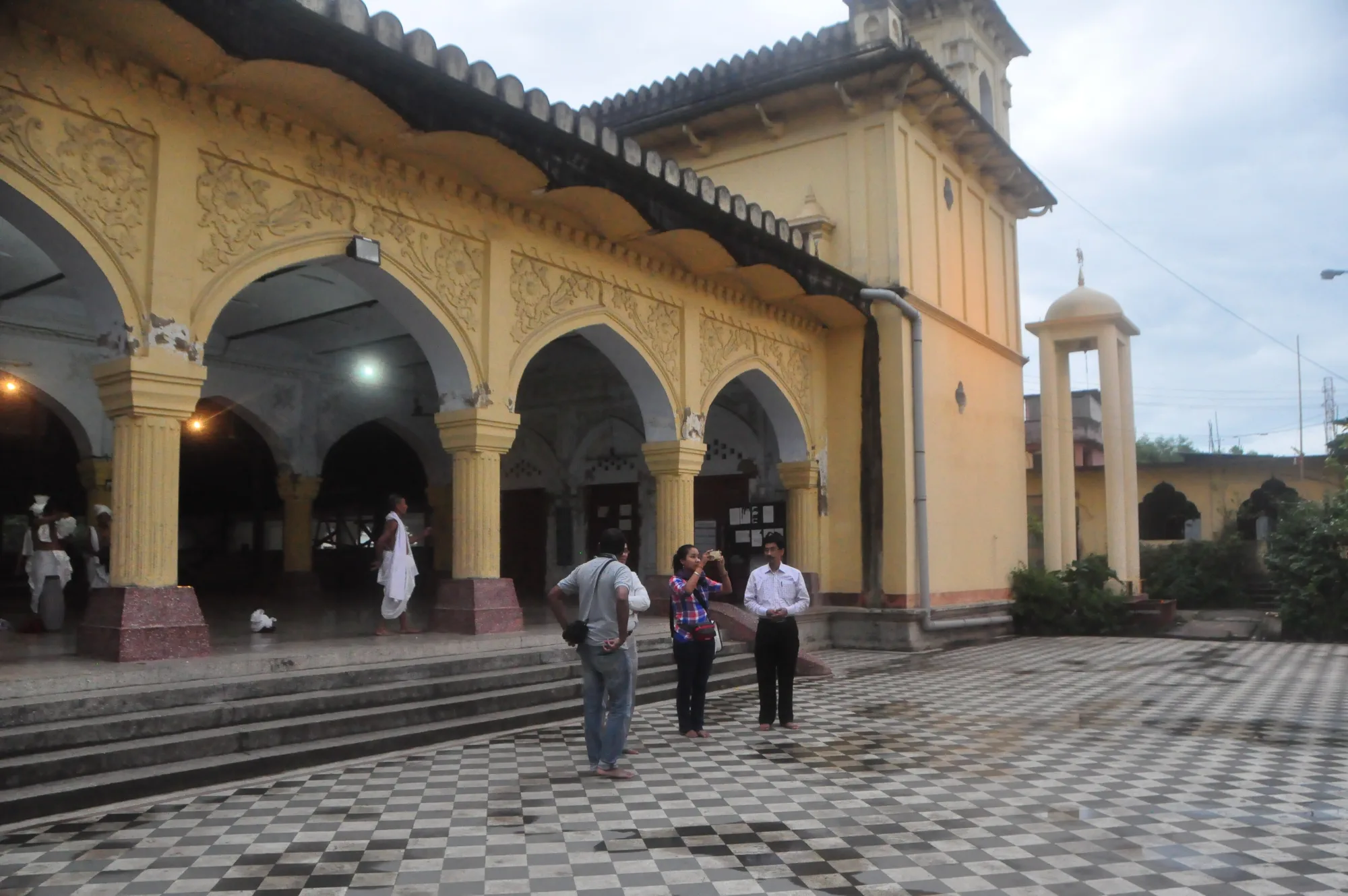 The arched frontage of a Manipur temple, visitors crossing the tiled forecourt