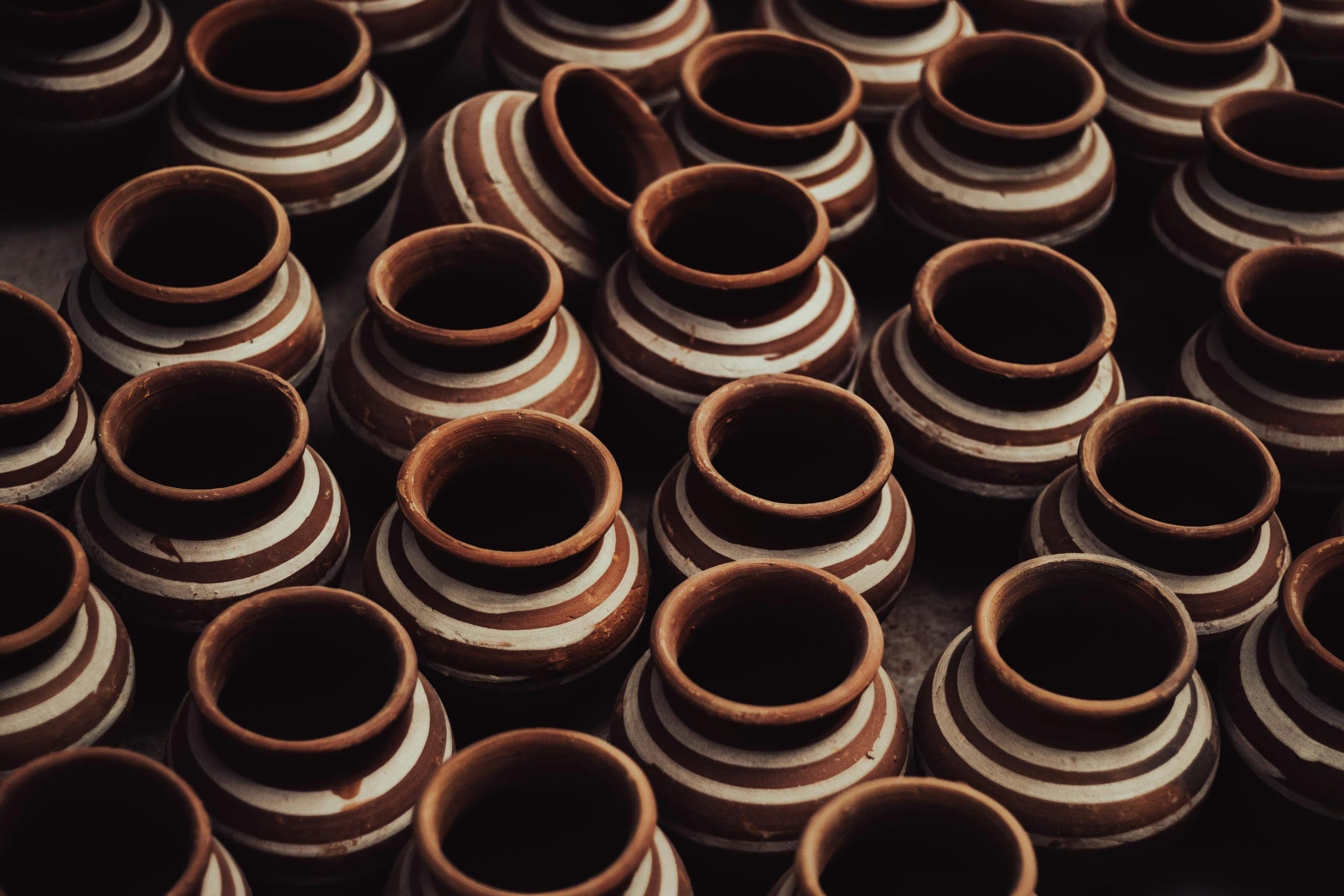 Hands shaping a clay pot by the coil-and-beat method at Andro