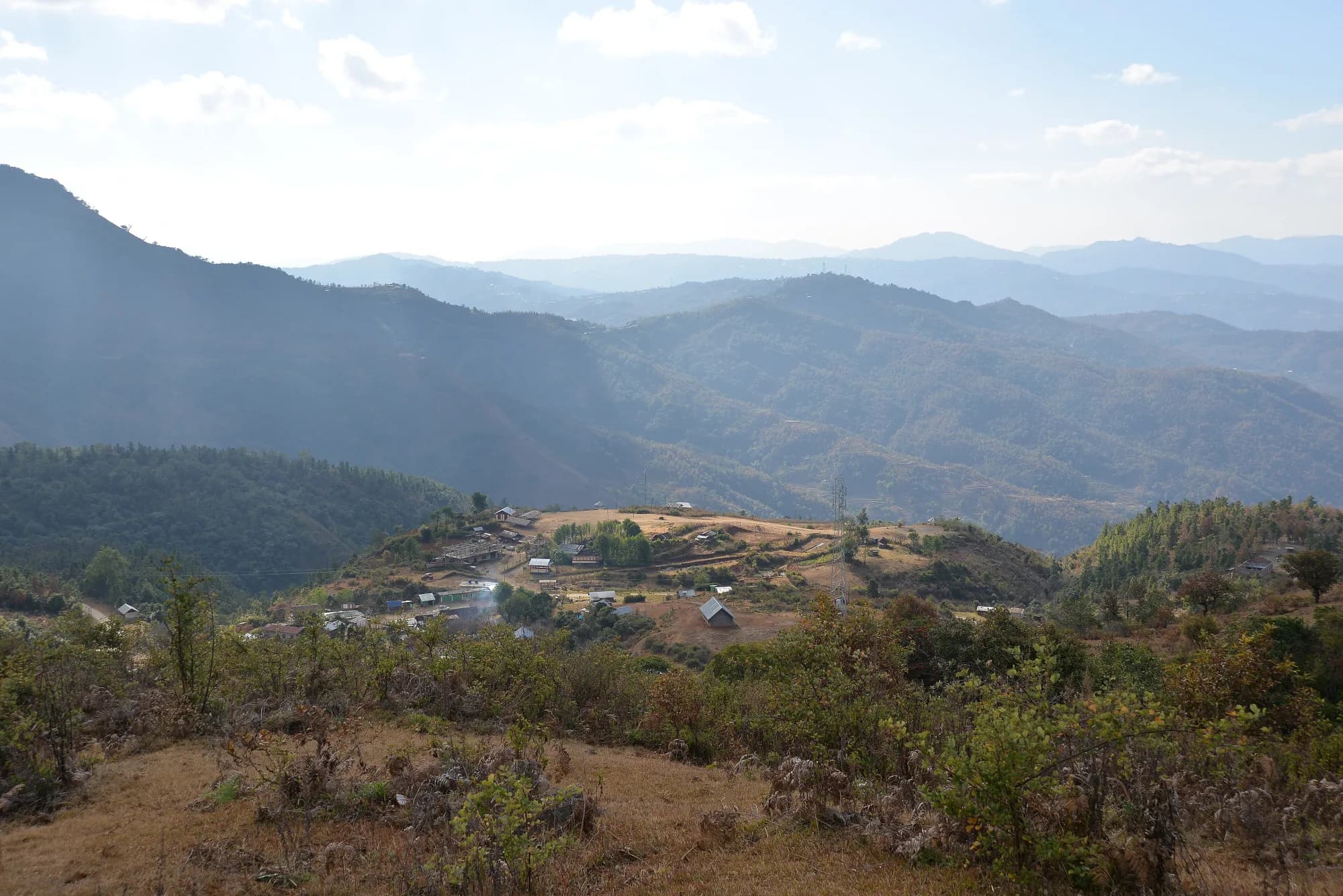 Layered hills fading into blue haze above a village in Ukhrul district